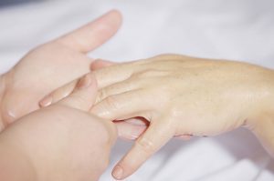 Picture of oiled hand touching and massaging another hand.
