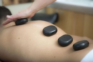 Picture of hot stones massage on a mans back.