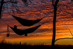 Photo of someone in a hammock at sunset. De-stress yourself.