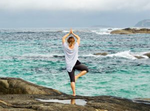 Woman by the ocean being mindful with yoga