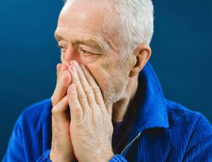 Older guy stressed hands covering face